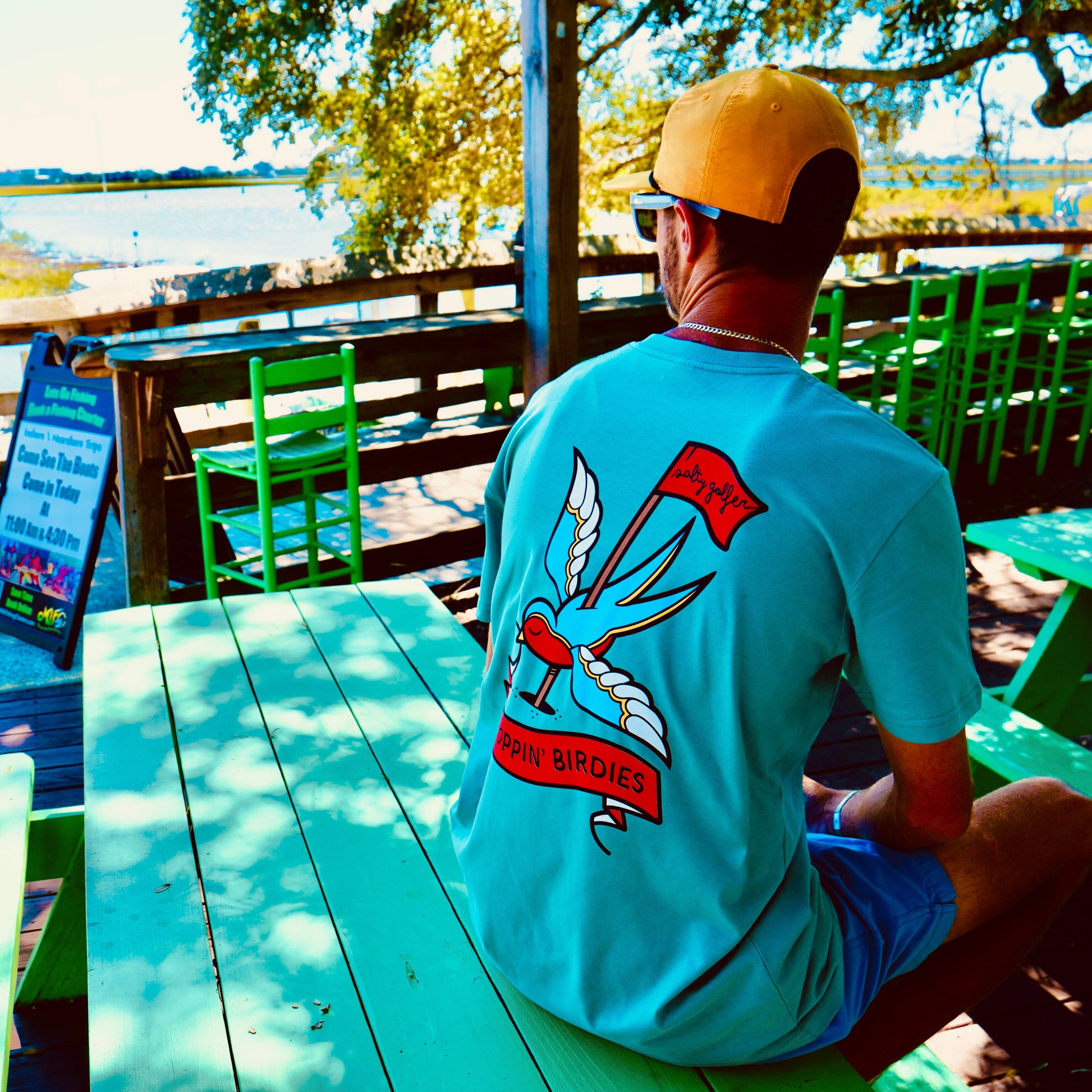 Droppin birdies t shirt aqua green man sitting on dock looking out at murrells inlet marsh walk wearing new salty golfer t shirt