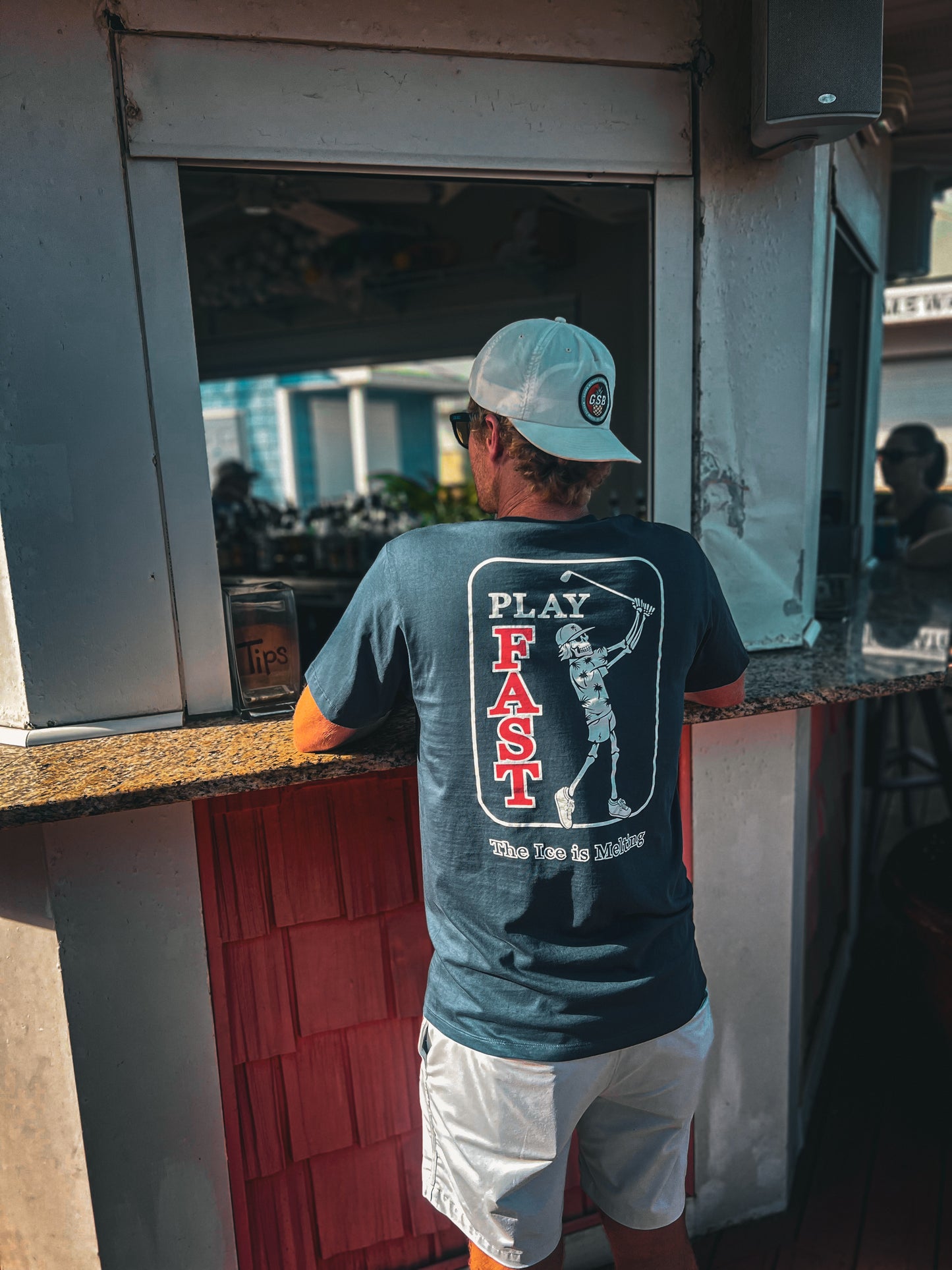 Man standing and facing the bar wearing a play fast the ice is melting T shirt